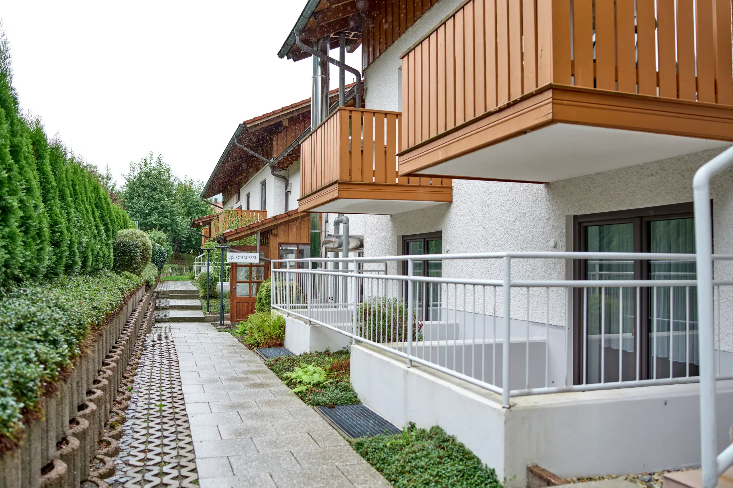 Aussenansicht der Arberherz Apartments mit Balkonen und Heckenweg