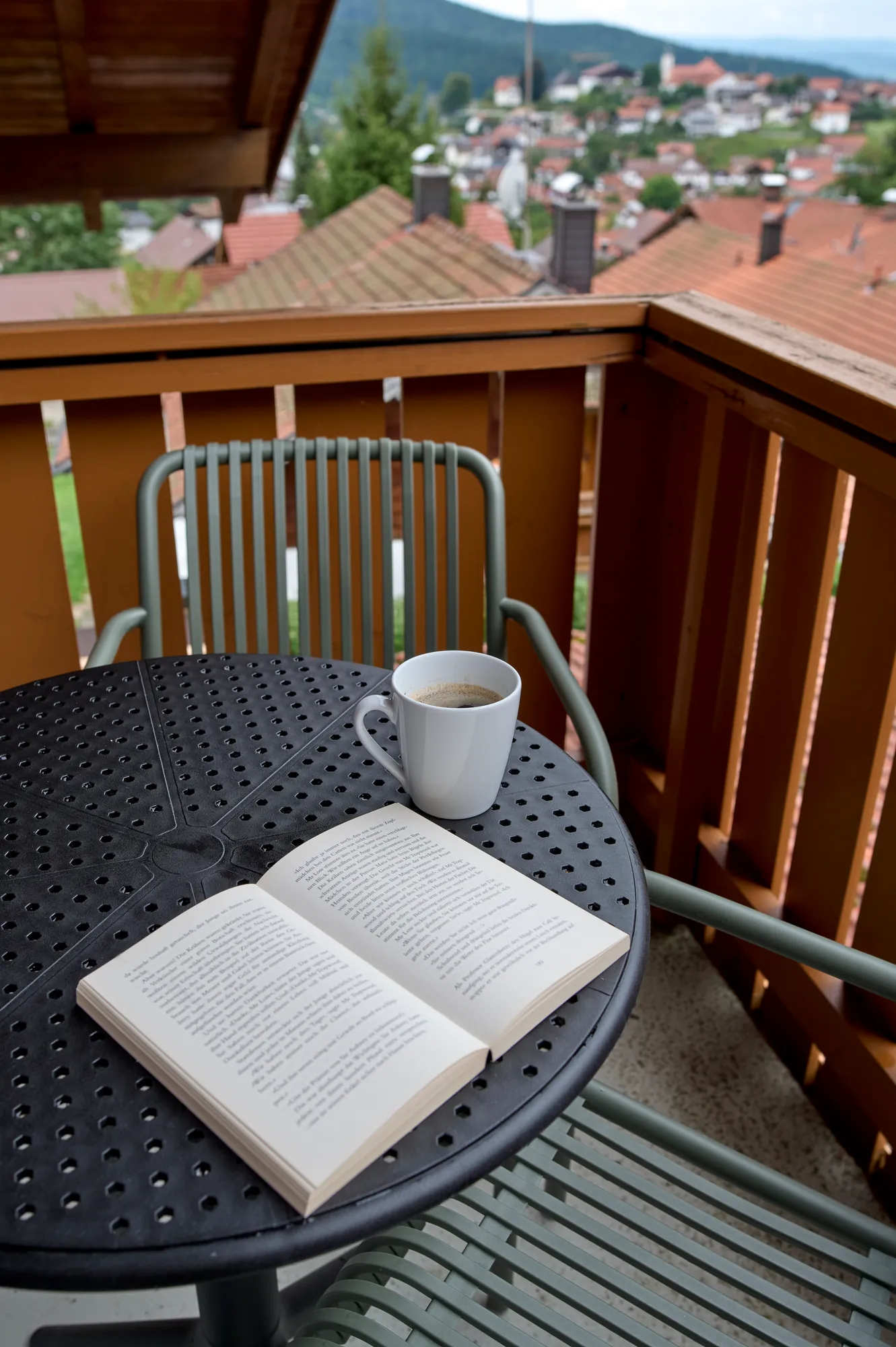 Kaffee und Buch auf dem Balkontisch