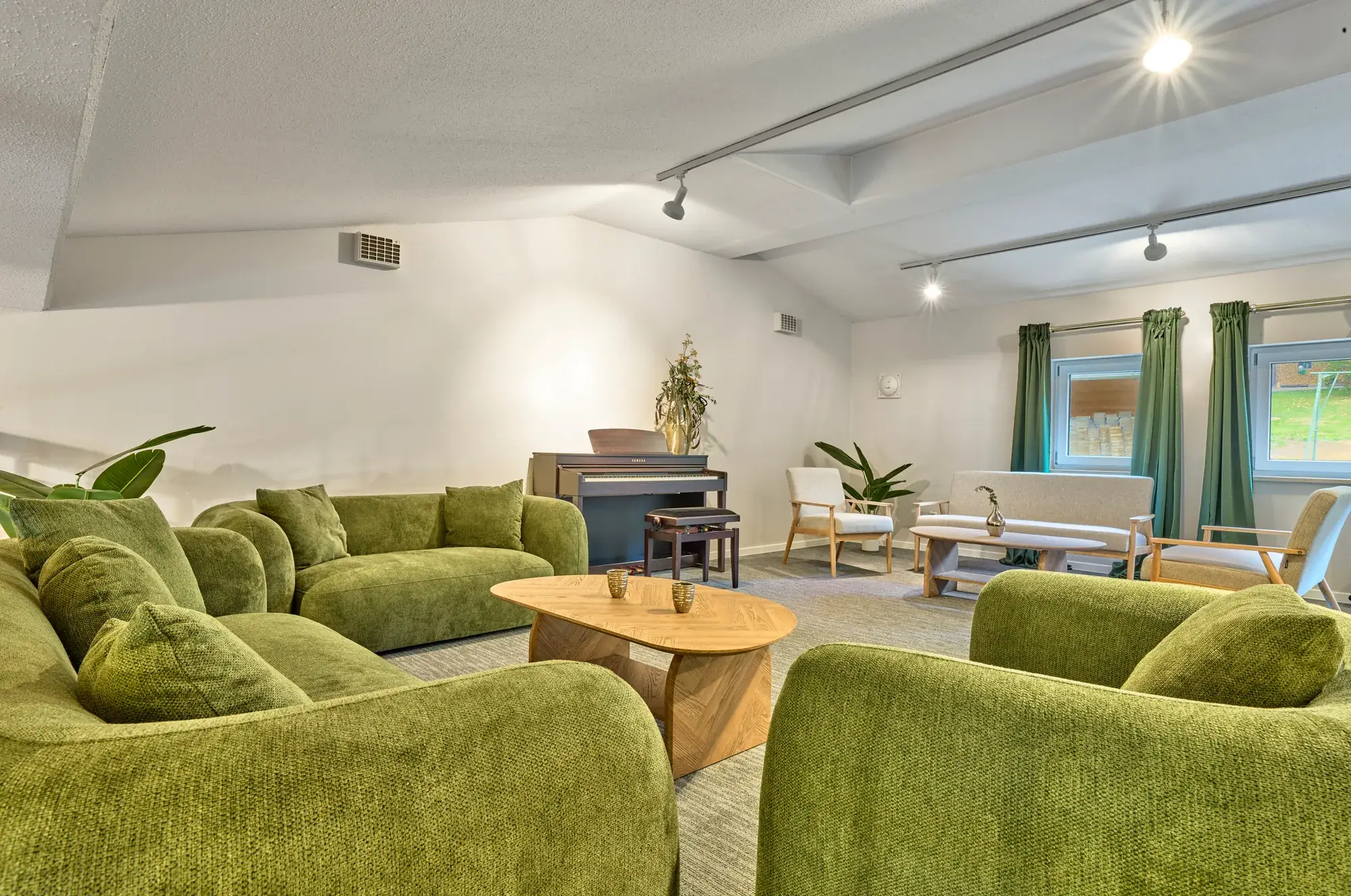 Gemeinschaftslounge mit gruenen Sitzgruppen